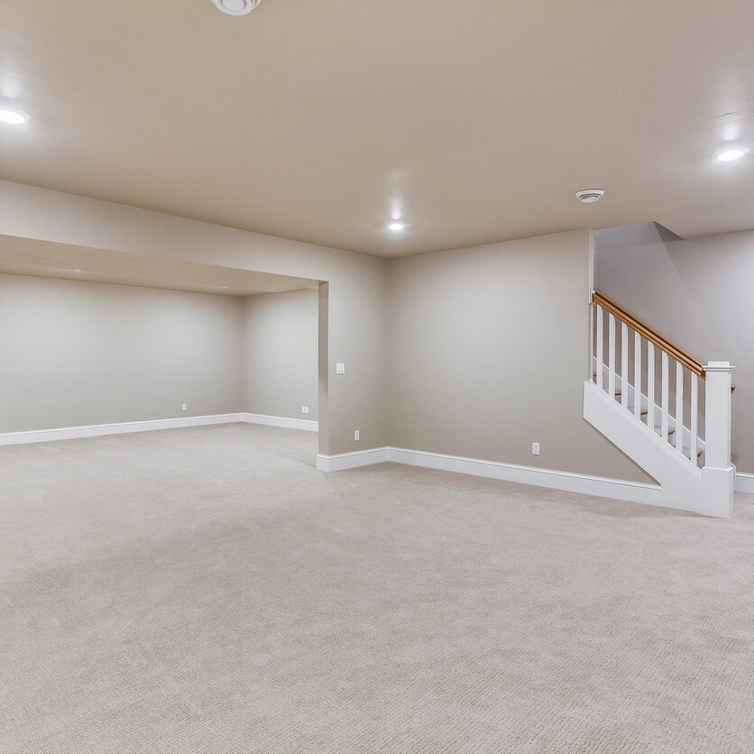 Light colored carpet with plenty of LED wafer lights to make this basement bright